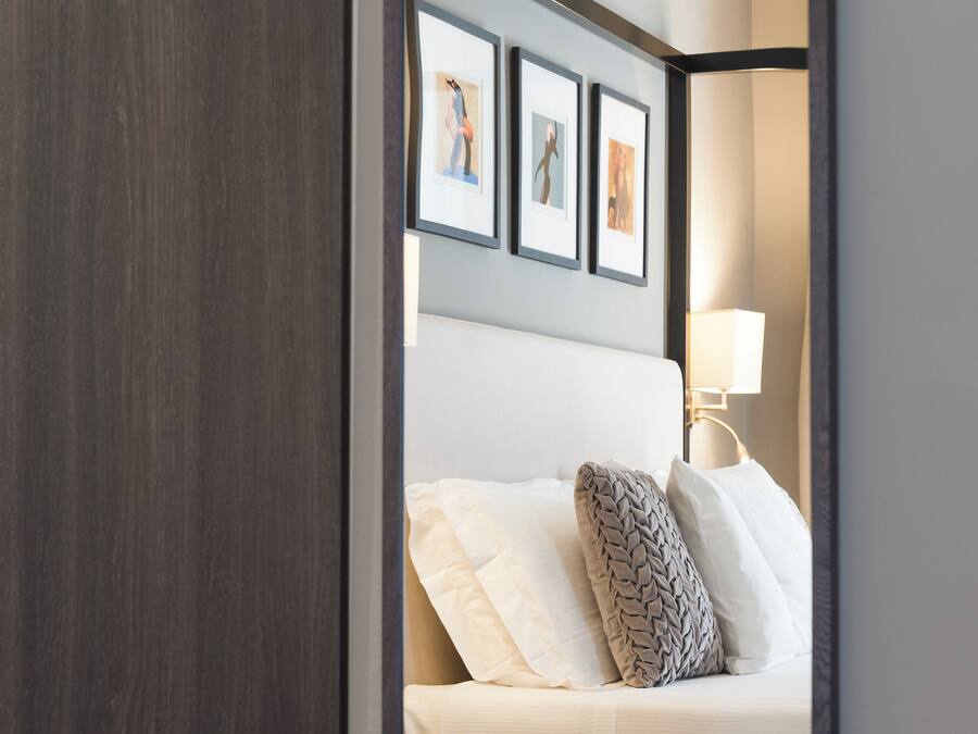 A bedroom with a bed, a bedside table, a lamp, and framed pictures on the wall.