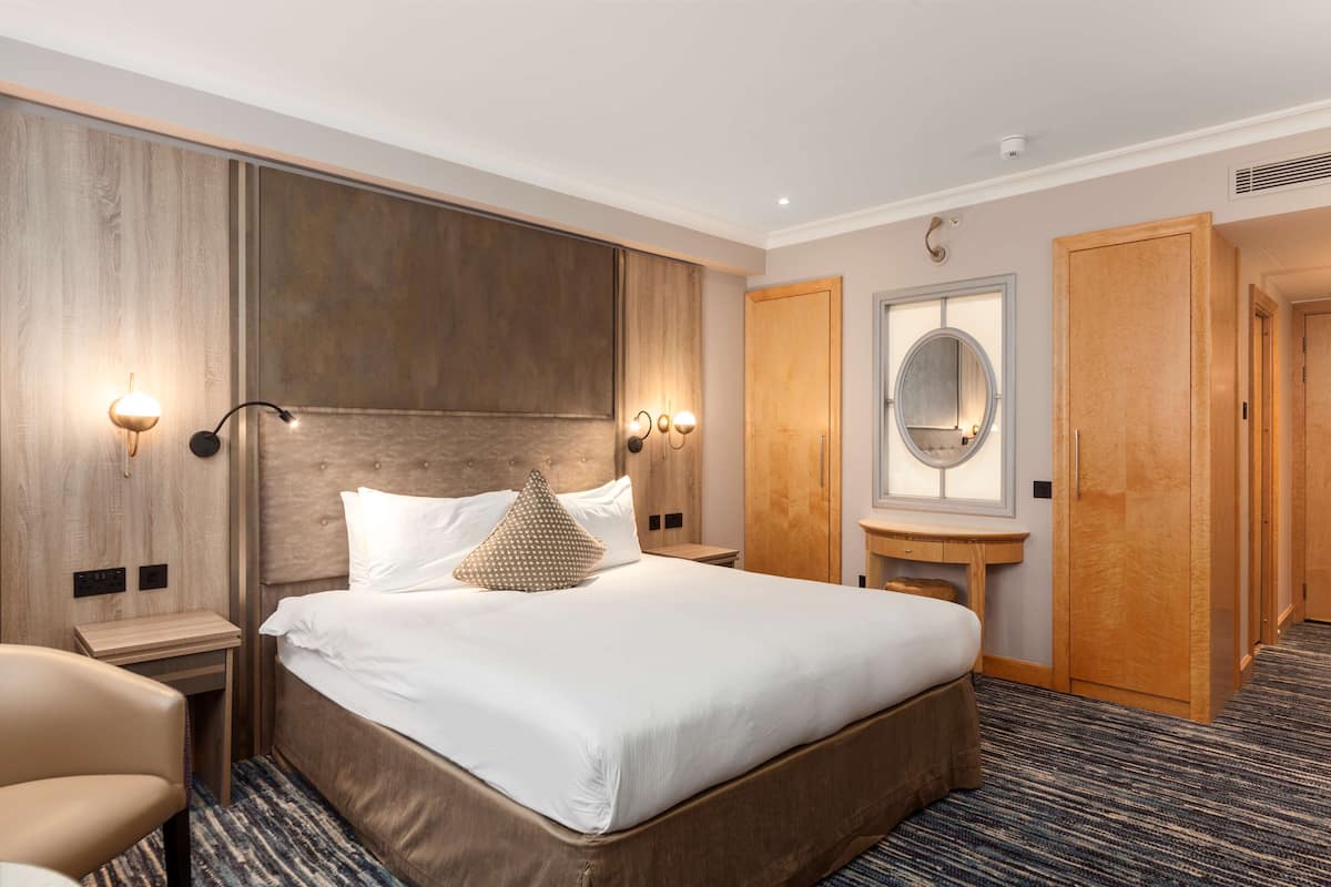 Ein Hotelzimmer mit einem großen Bett, Nachttischen, einem Spiegel und einem Kleiderschrank.
