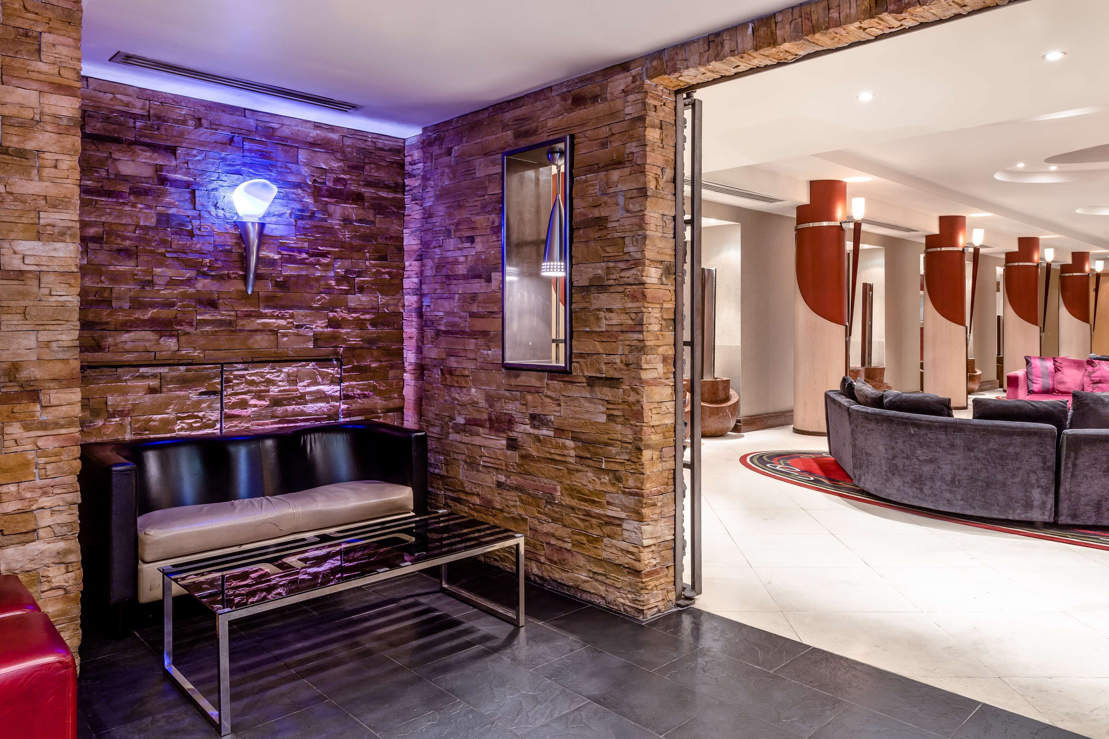 A modern lobby with a stone wall, a bench, a sofa, and a mirror.