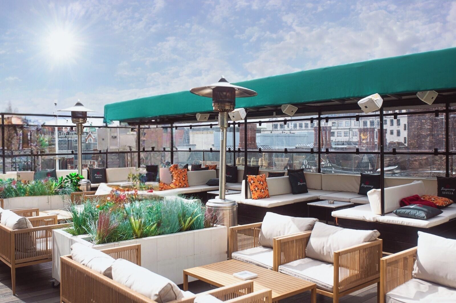 A rooftop terrace with outdoor seating, a green awning, and a view of the cityscape.