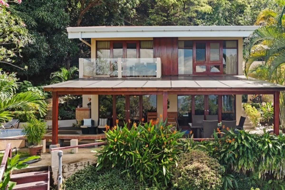 Ein zweistöckiges Haus mit überdachter Terrasse und Balkon.
