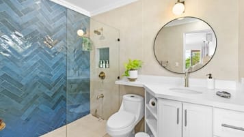 Un baño moderno con un lavabo blanco, un espejo redondo y un inodoro.