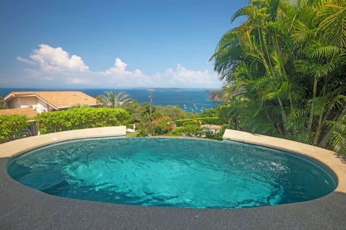 Ein Pool mit Blick auf den Ozean und Palmen.