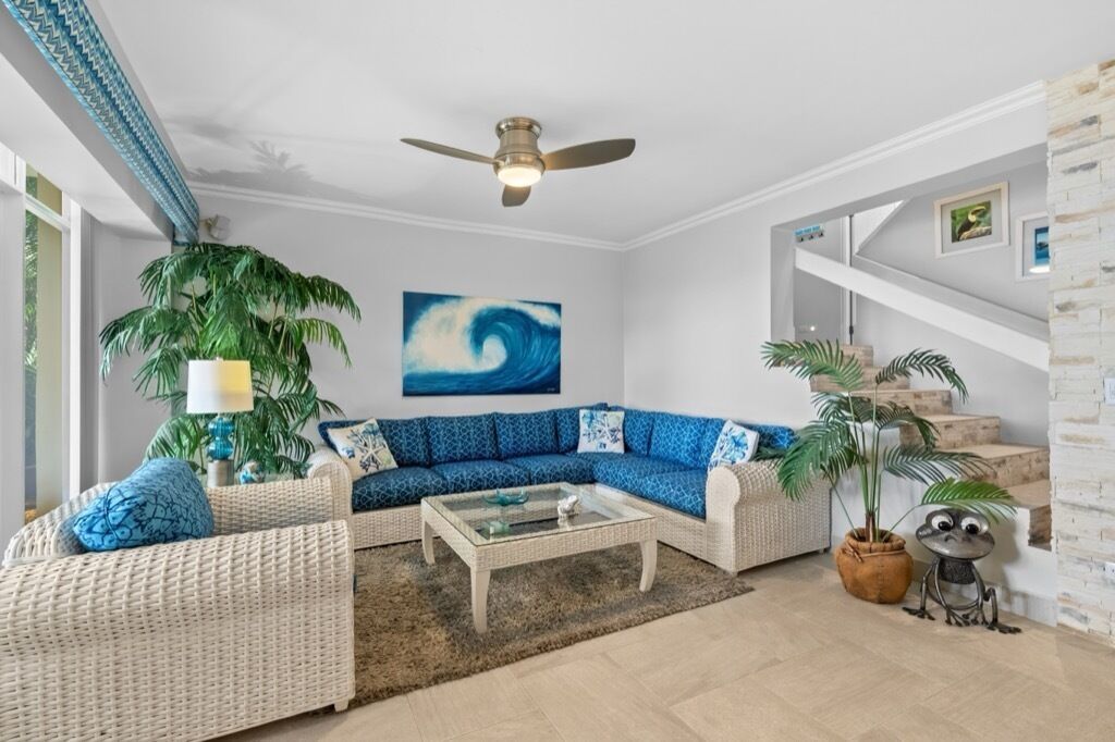 A living room with a blue sofa, a coffee table, and a ceiling fan.