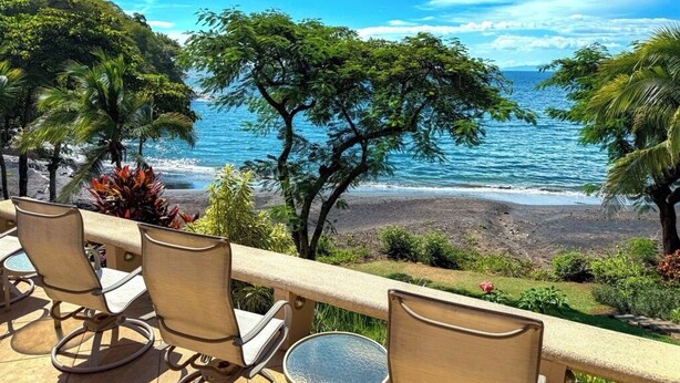 Une terrasse avec des chaises et une table, d’où l’on a vue sur une plage et l’océan.