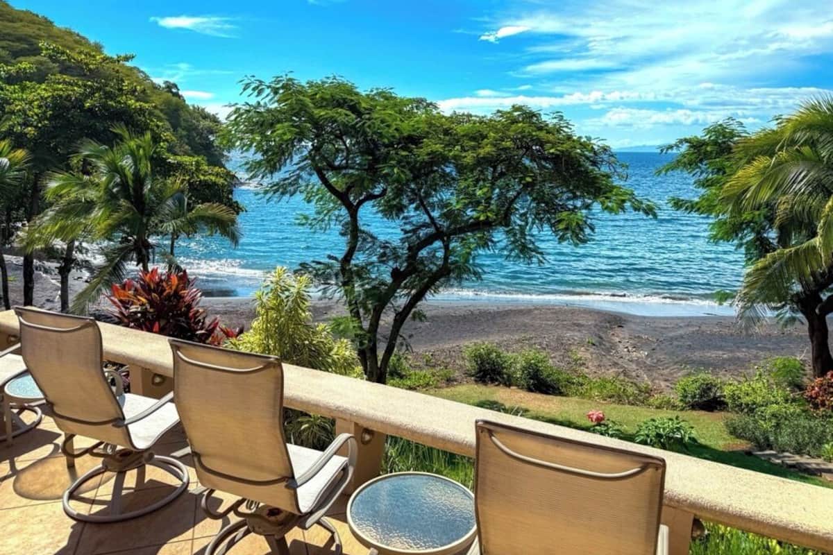 Eine Terrasse mit Stühlen und Tisch mit Blick auf Strand und Meer.