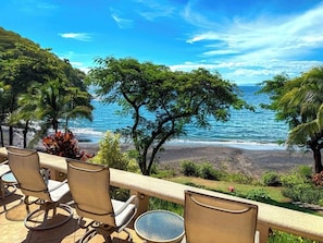 Una terraza con sillas y una mesa, con vista a una playa y al océano.
