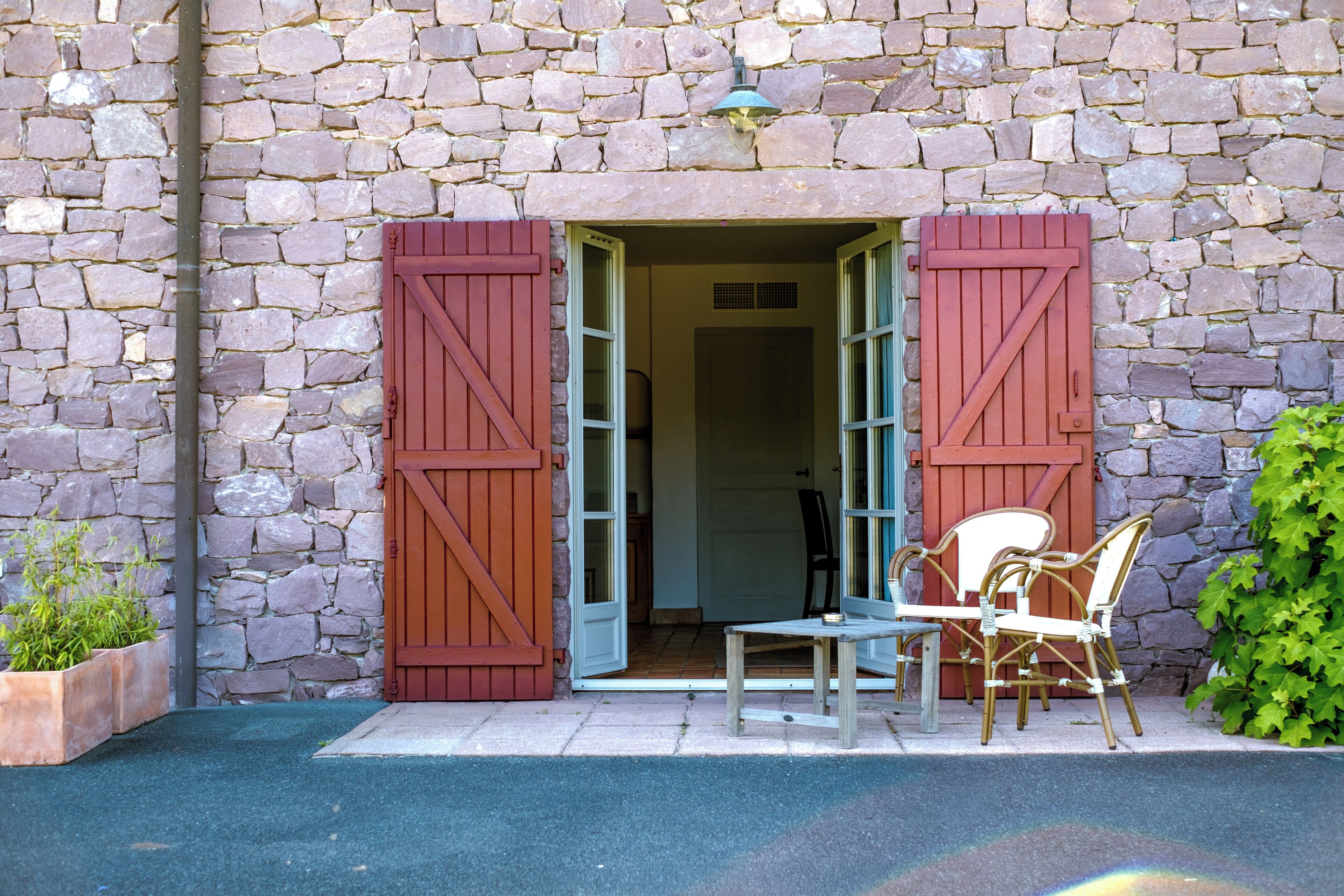 Un bâtiment en pierre avec une porte en bois et une petite table entourée de chaises à l’extérieur.