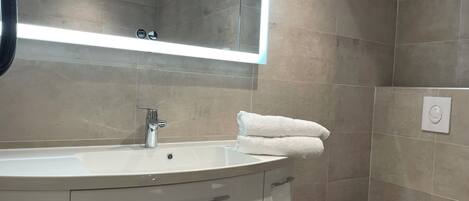 Ein modernes Badezimmer mit einem großen Waschbecken, einem Spiegel und einer Toilette.