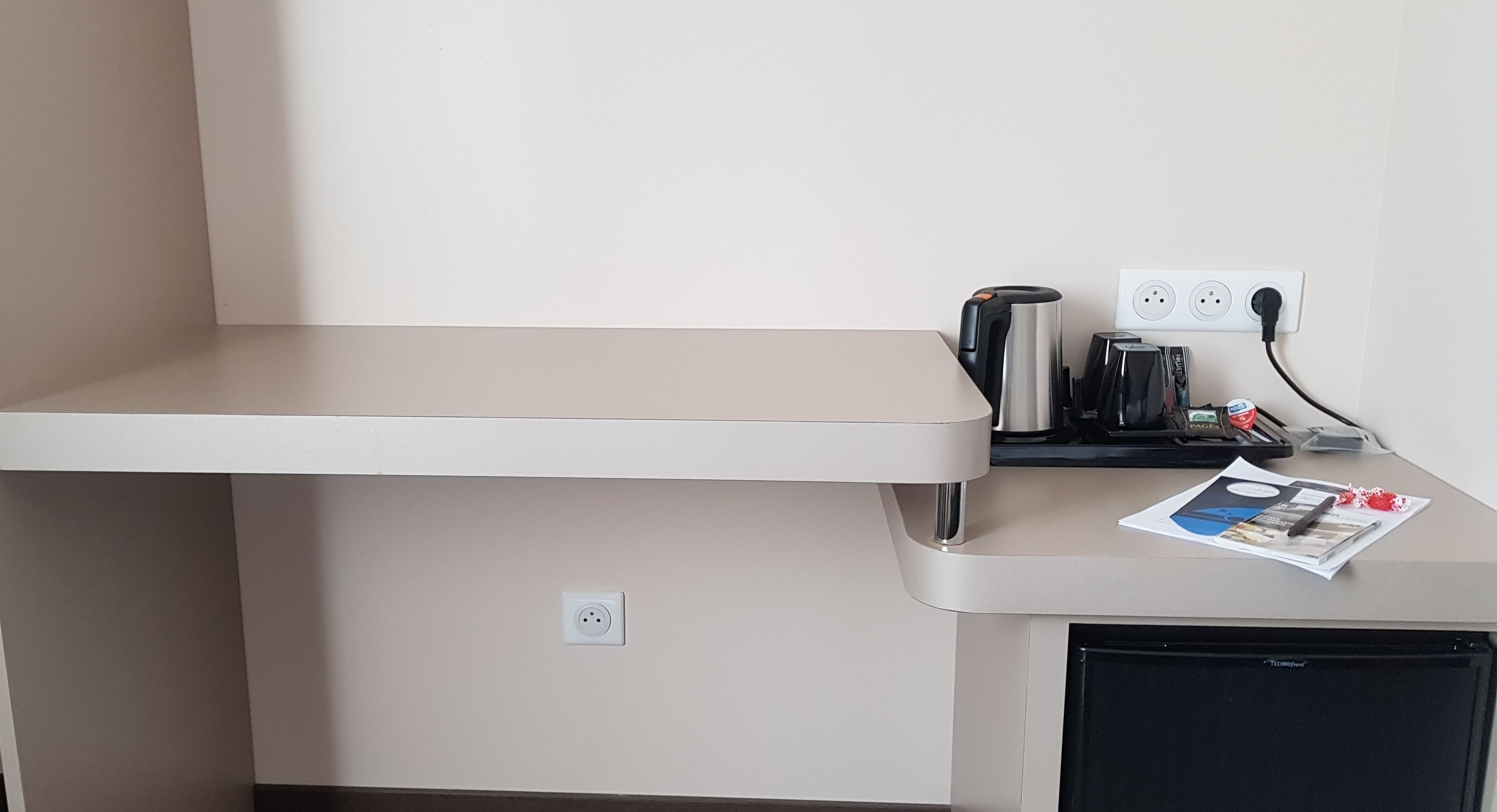 Una kitchenette equipada con cafetera, hervidor y refrigerador pequeño.