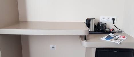 Una kitchenette equipada con cafetera, hervidor y refrigerador pequeño.