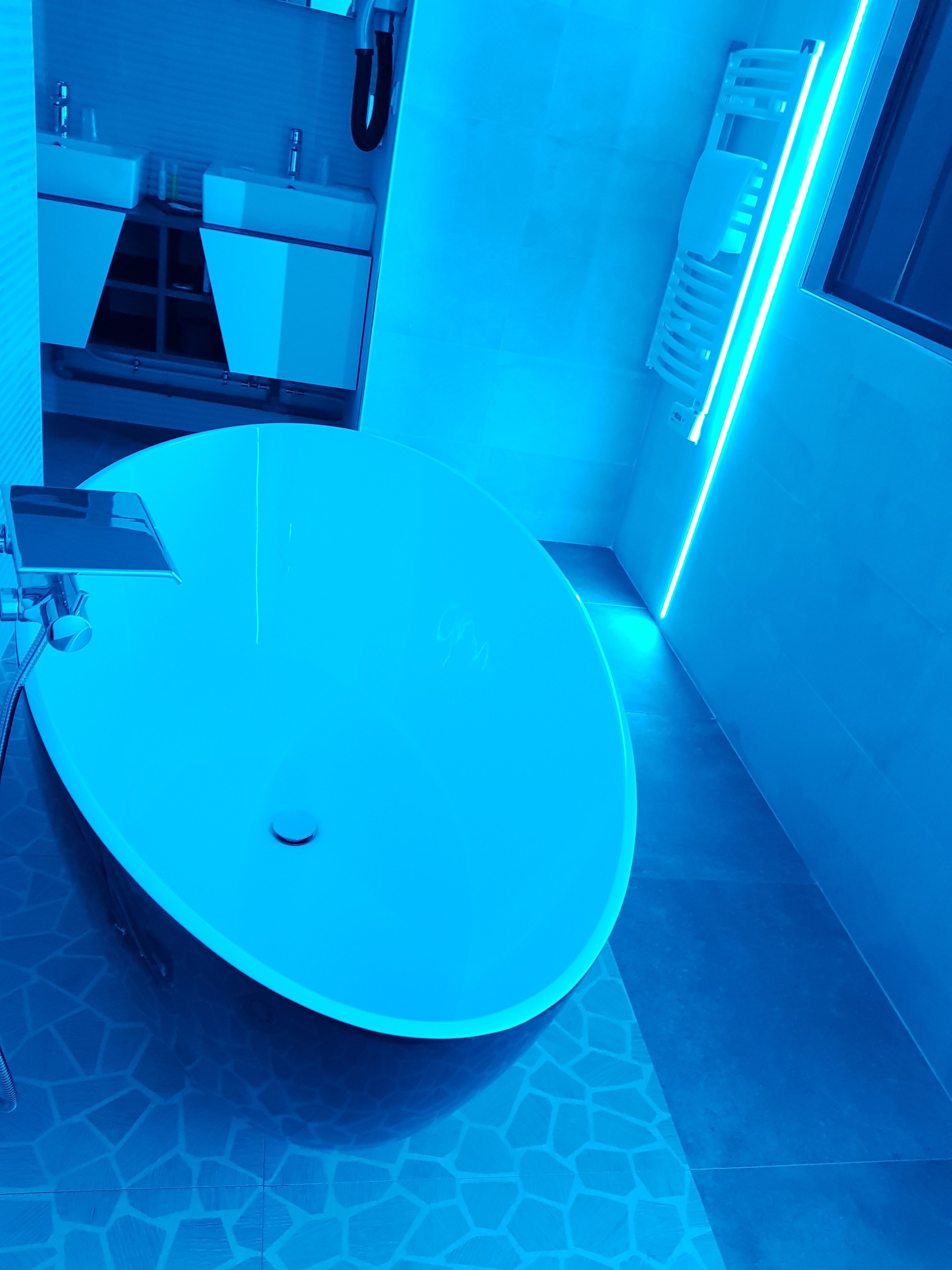 A modern bathroom with a large, round sink and a handheld mirror.