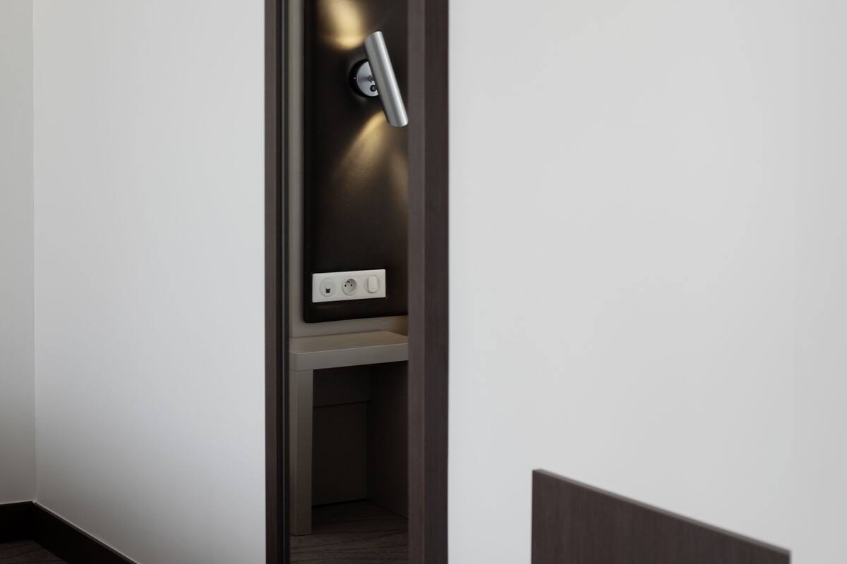 A modern, minimalist room with a built-in bench and a wall-mounted shelf with a light.