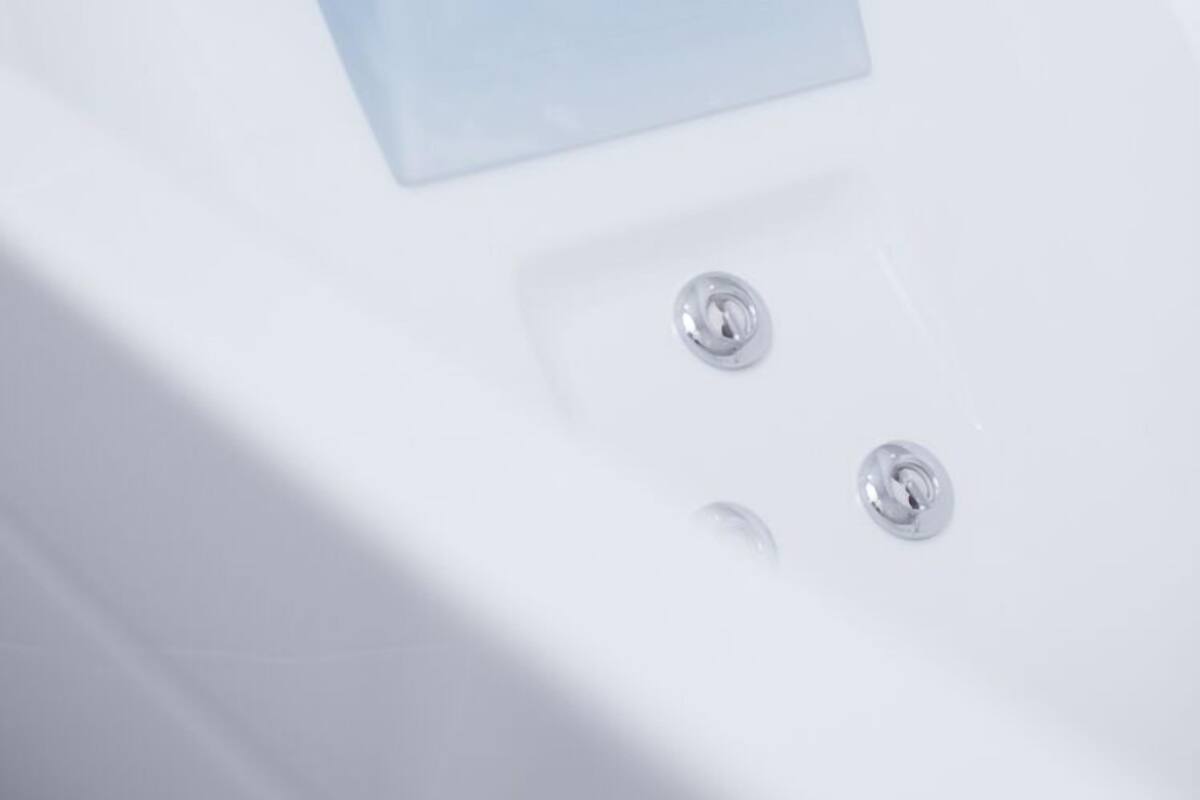 A white bathtub with a clear blue bath mat.