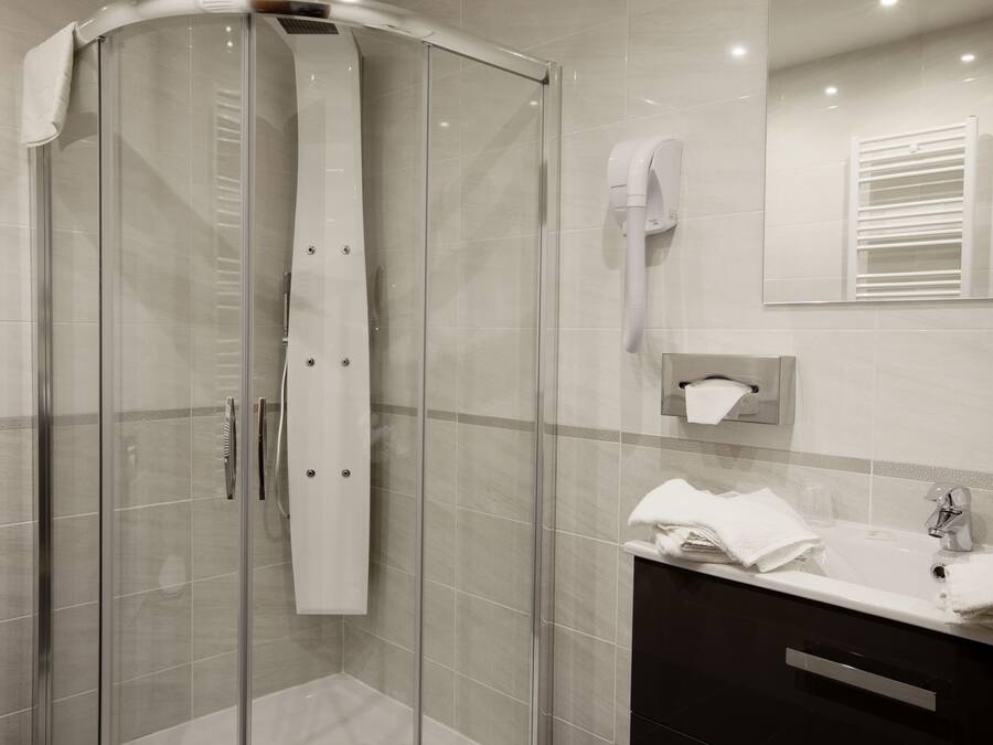Un baño moderno con ducha de vidrio, tocador con lavamanos y un perchero para toallas.