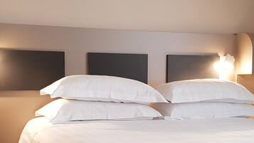 Une chambre d’hôtel avec un grand lit, deux lampes de chevet et un luminaire fixé au mur.
