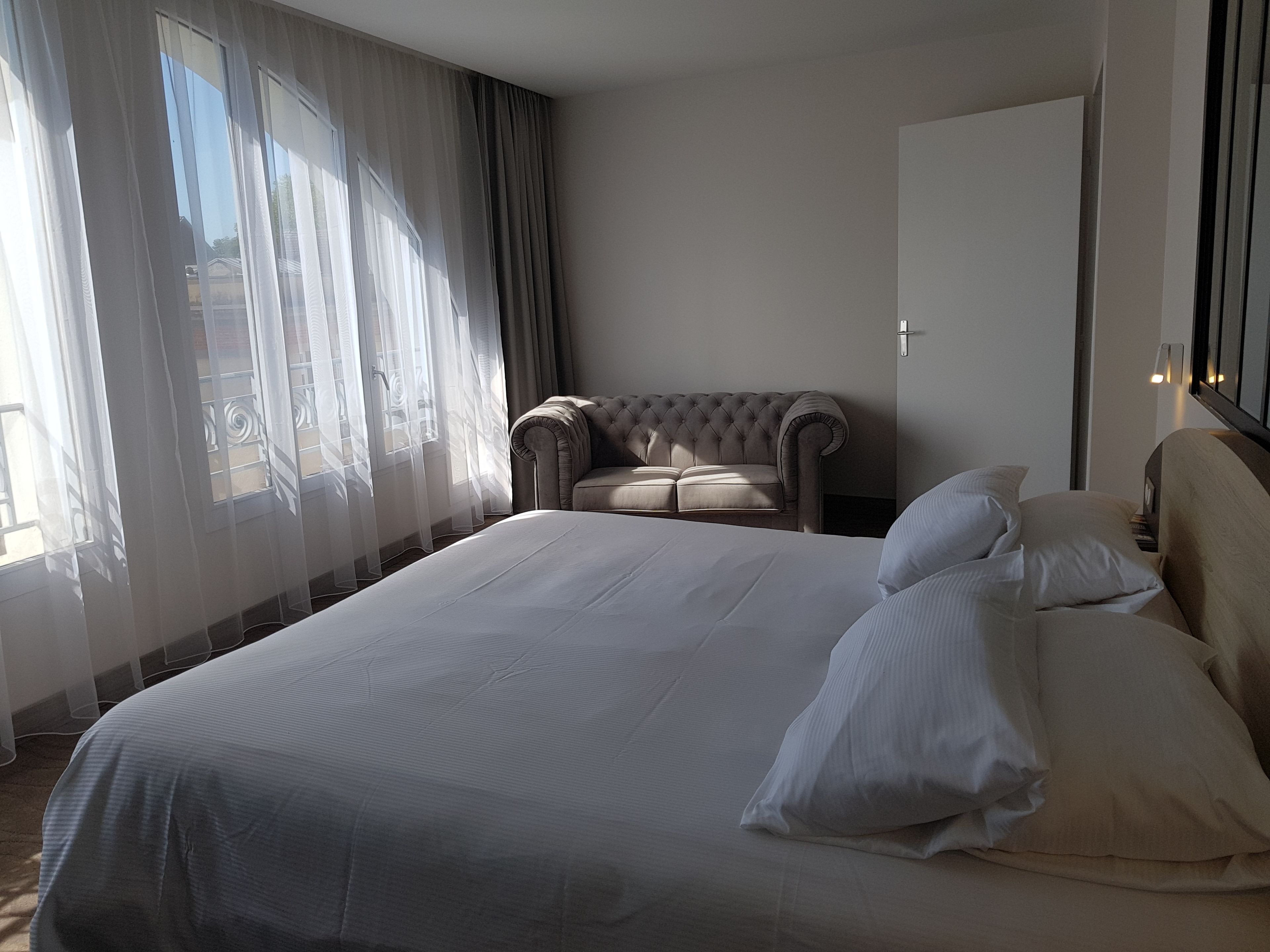 A hotel room with a large bed, a sofa, and a view of the outside.