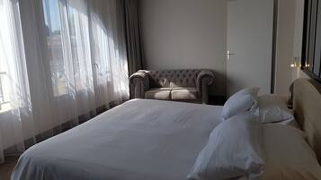 A hotel room with a large bed, a sofa, and a view of the outside.