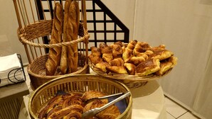 A variety of baked goods displayed in baskets and a bowl, including baguettes, croissants, and pastries. - Brit Hotel de Grignan (Vichy)