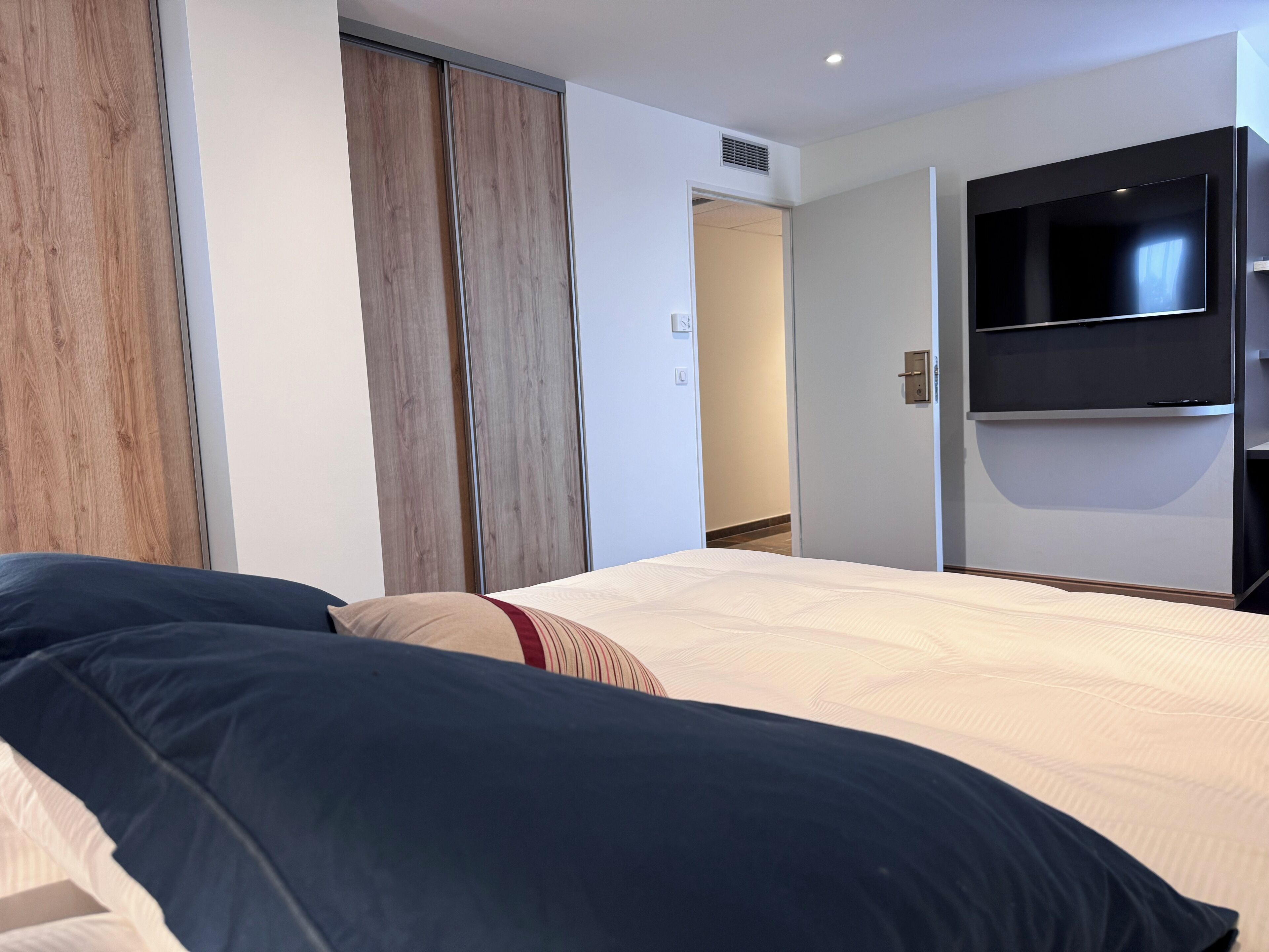 Une chambre à coucher avec un lit, une armoire et un téléviseur fixé au mur.