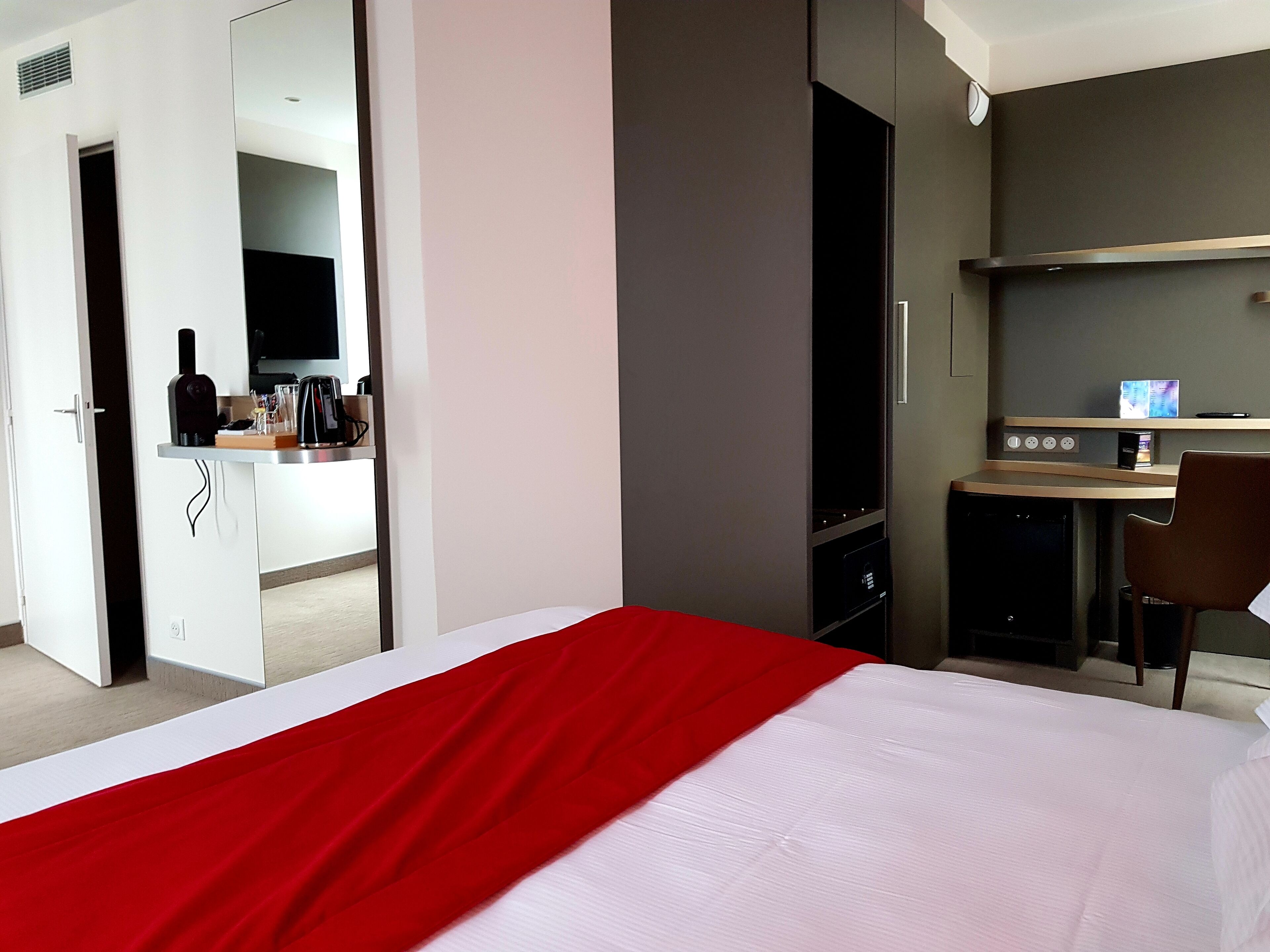 Una habitación de hotel con cama, escritorio y espejo.