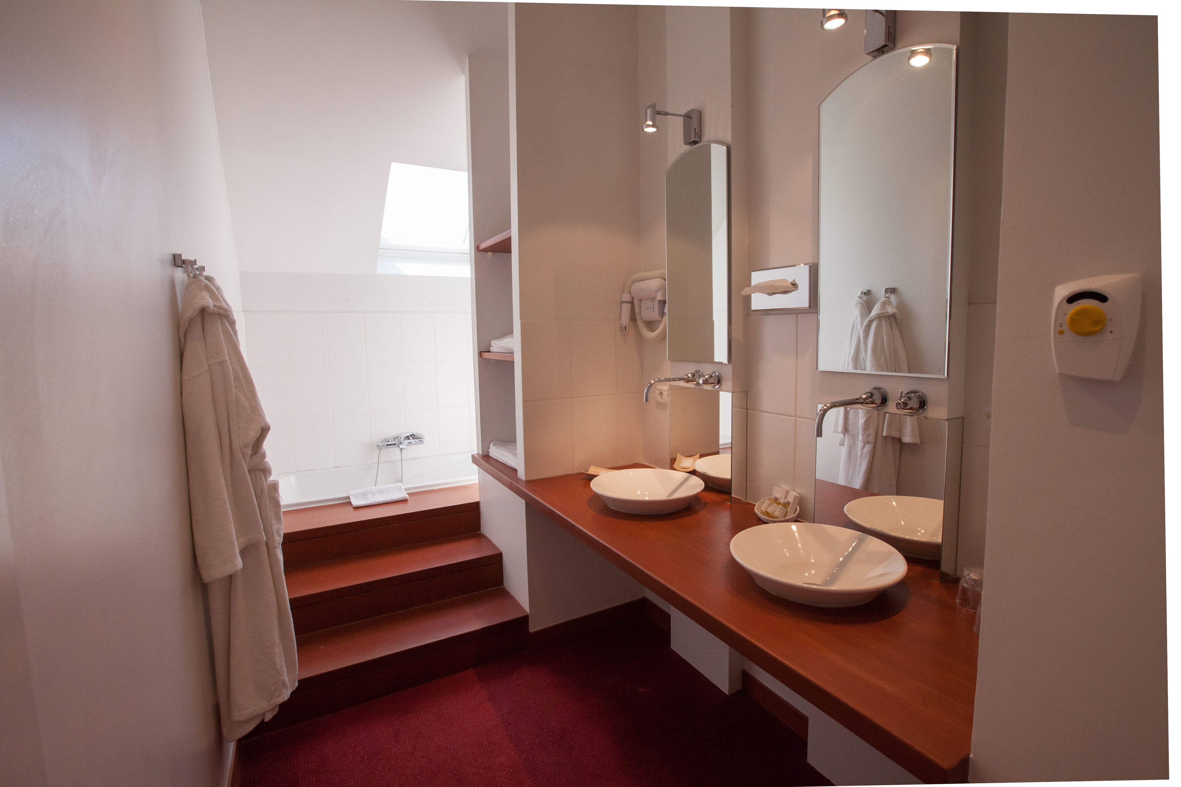Une salle de bain moderne avec deux lavabos, un grand miroir et un porte-serviettes.