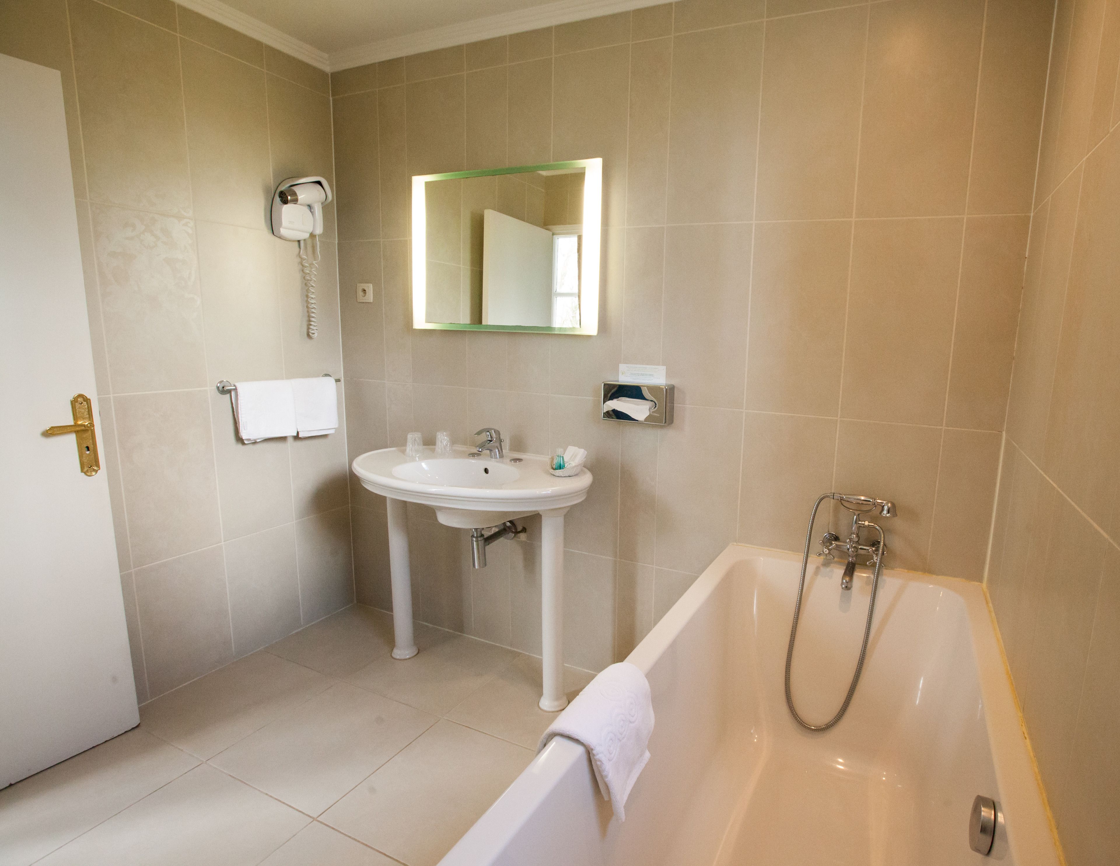 A bathroom with a sink, mirror, and bathtub.