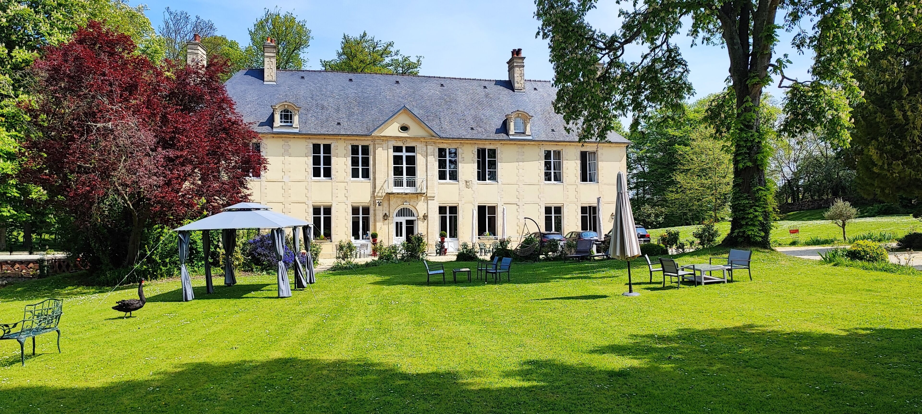 A large, two-story house with a well-maintained lawn and outdoor seating area.