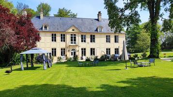 A large, two-story house with a well-maintained lawn and outdoor seating area.