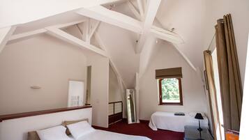 Ein Schlafzimmer mit zwei Betten, einem fensterförmigen Ausblick, einem Spiegel und einer Treppe zu einem weiteren Raum.