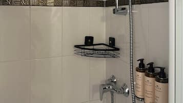 Une salle de bain moderne équipée d’une douche, d’un porte-serviettes et d’un distributeur de savon.