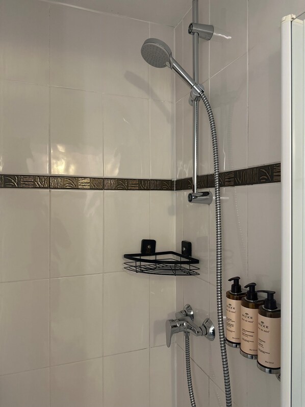 A modern bathroom with a shower, a towel rack, and a soap dispenser.