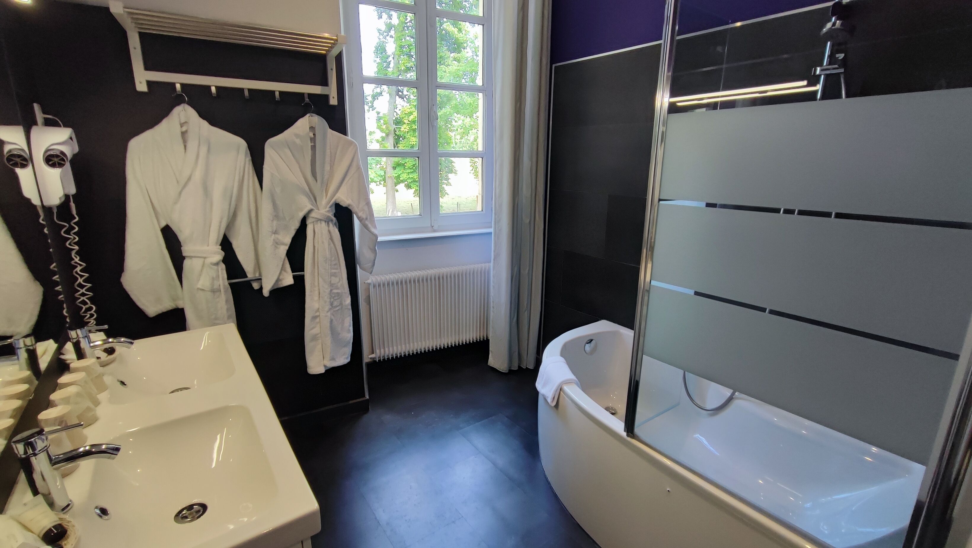 A modern bathroom with a white sink, a bathtub, and a window with curtains.