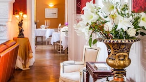 Un pasillo con una pared roja, una puerta blanca y una mesa con un jarrón de flores.