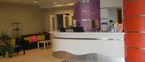 A reception area with a curved white reception desk, a purple accent wall, and a zebra-patterned rug.