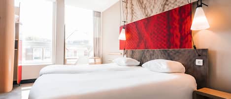 Habitación de hotel con una cama grande, una pared de acento roja y vistas a la ciudad.
