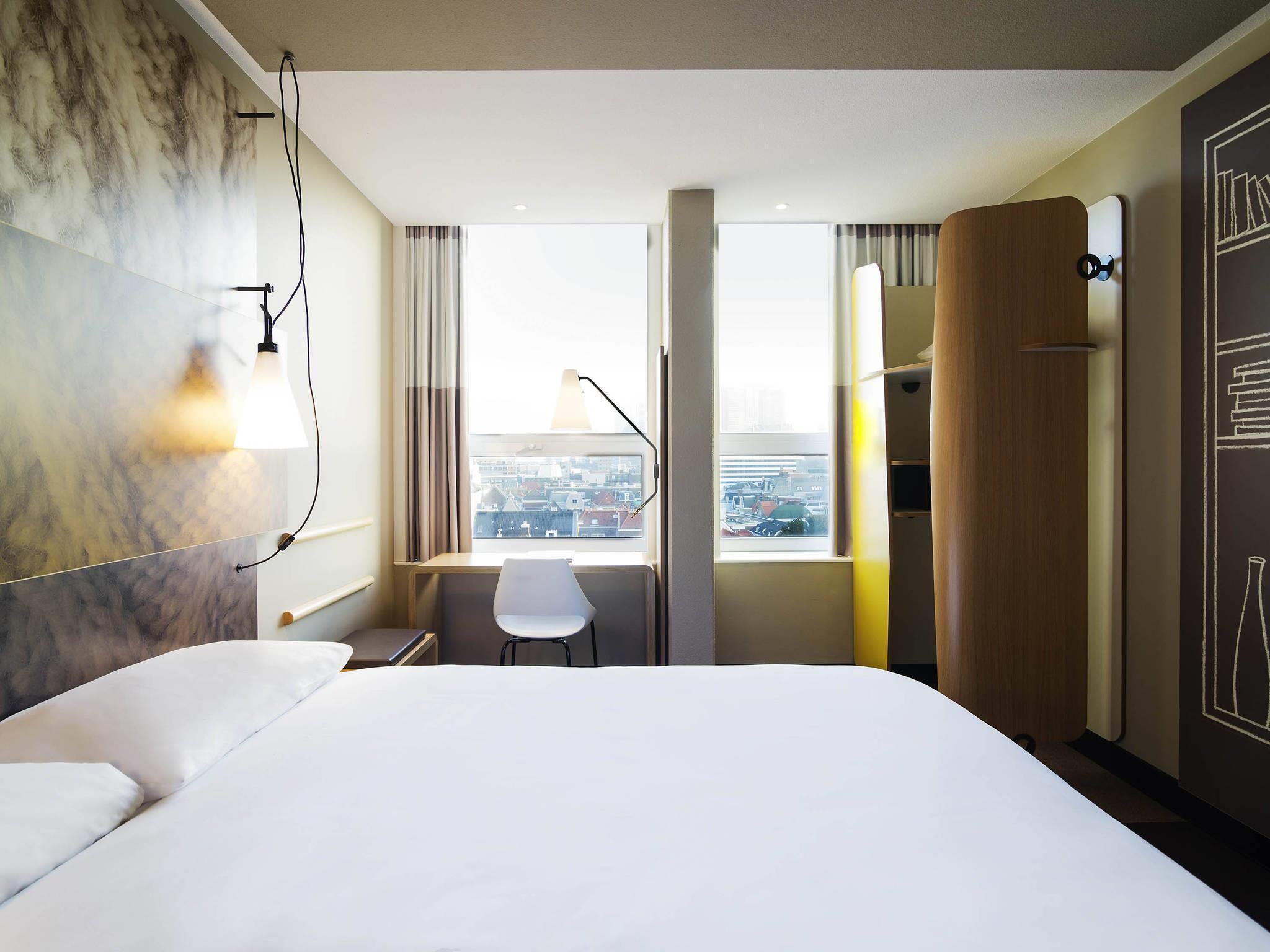 Een hotelkamer met een groot bed, een bureau, een stoel en een garderobe.