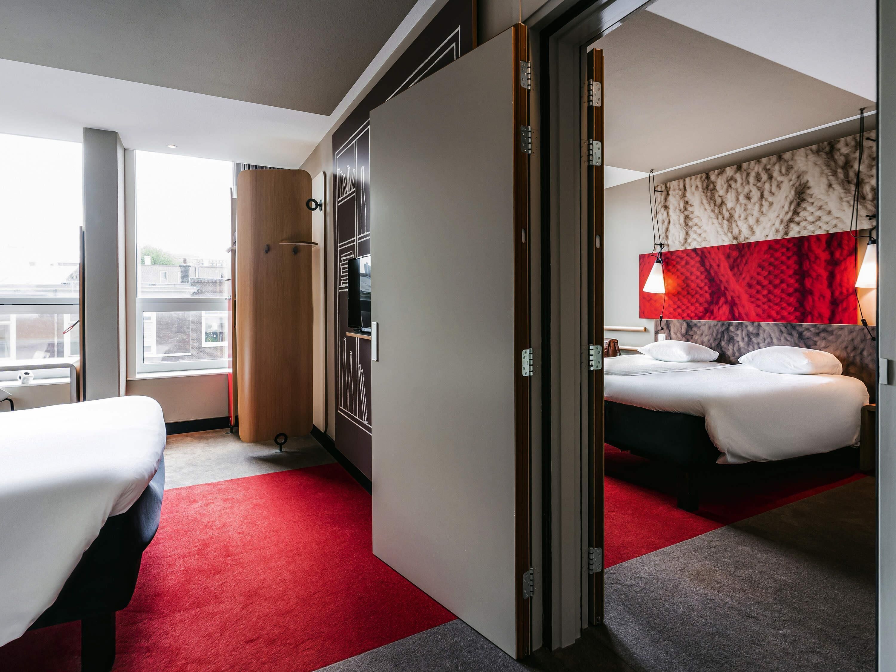 Ein Hotelzimmer mit Bett, Schreibtisch, Kleiderschrank und Blick auf die Stadt.