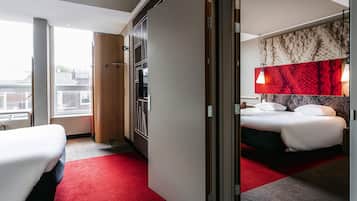 Ein Hotelzimmer mit Bett, Schreibtisch, Kleiderschrank und Blick auf die Stadt.