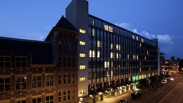 A modern hotel with multiple floors, large windows, and a well-lit exterior.