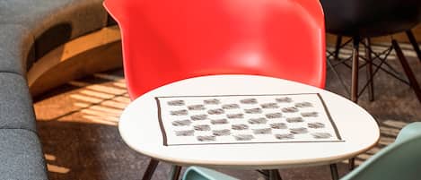 A modern seating area with a red chair, a round table with a patterned tablecloth, and a grey sofa.