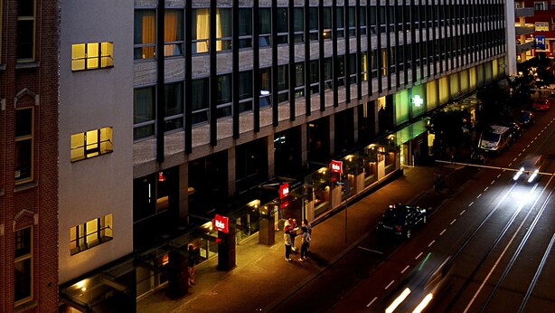 Een modern gebouw met meerdere verdiepingen, grote ramen en een commercieel gebied op de begane grond.