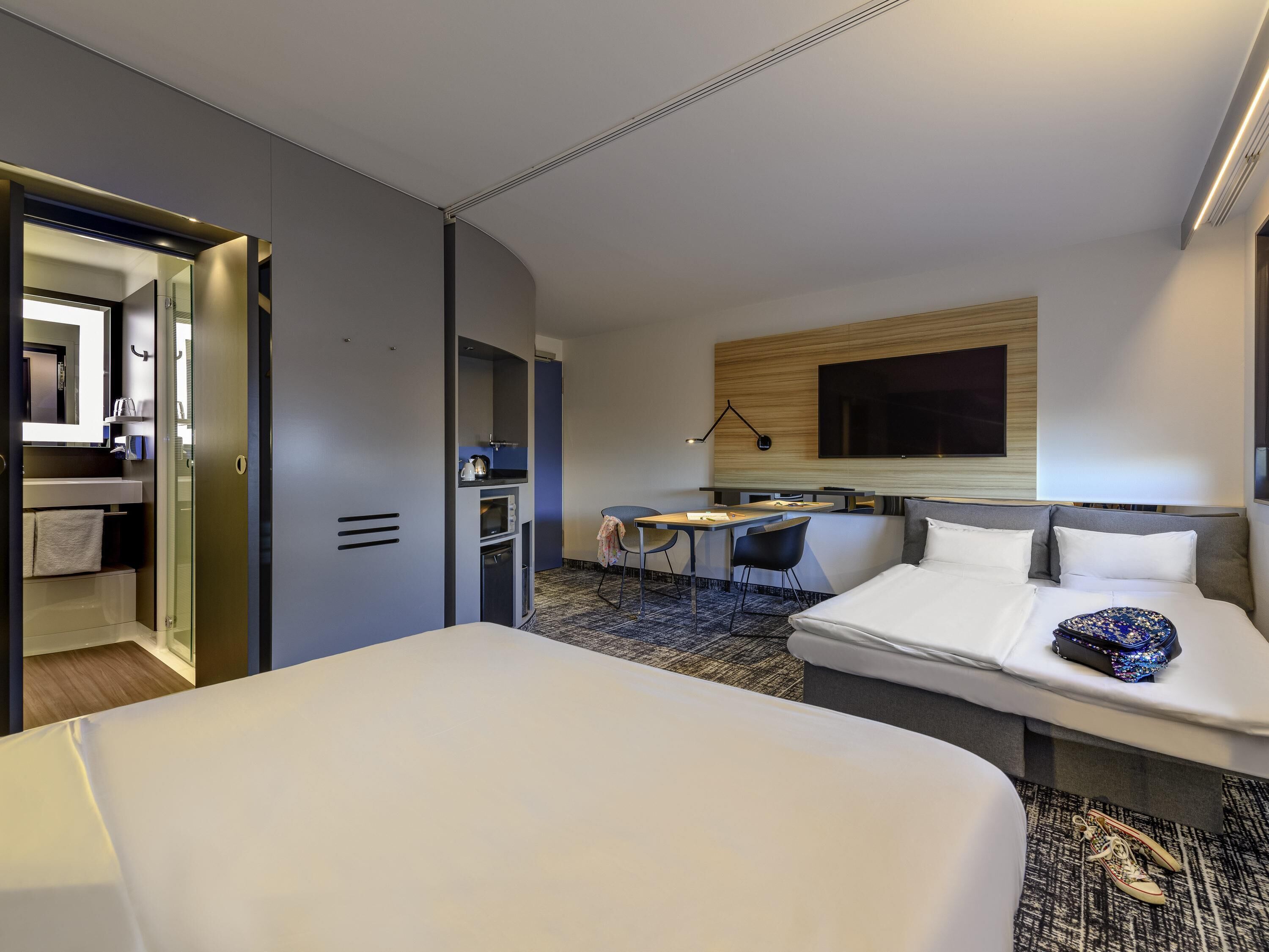 A hotel room with a bed, a desk, a TV, and a bathroom.