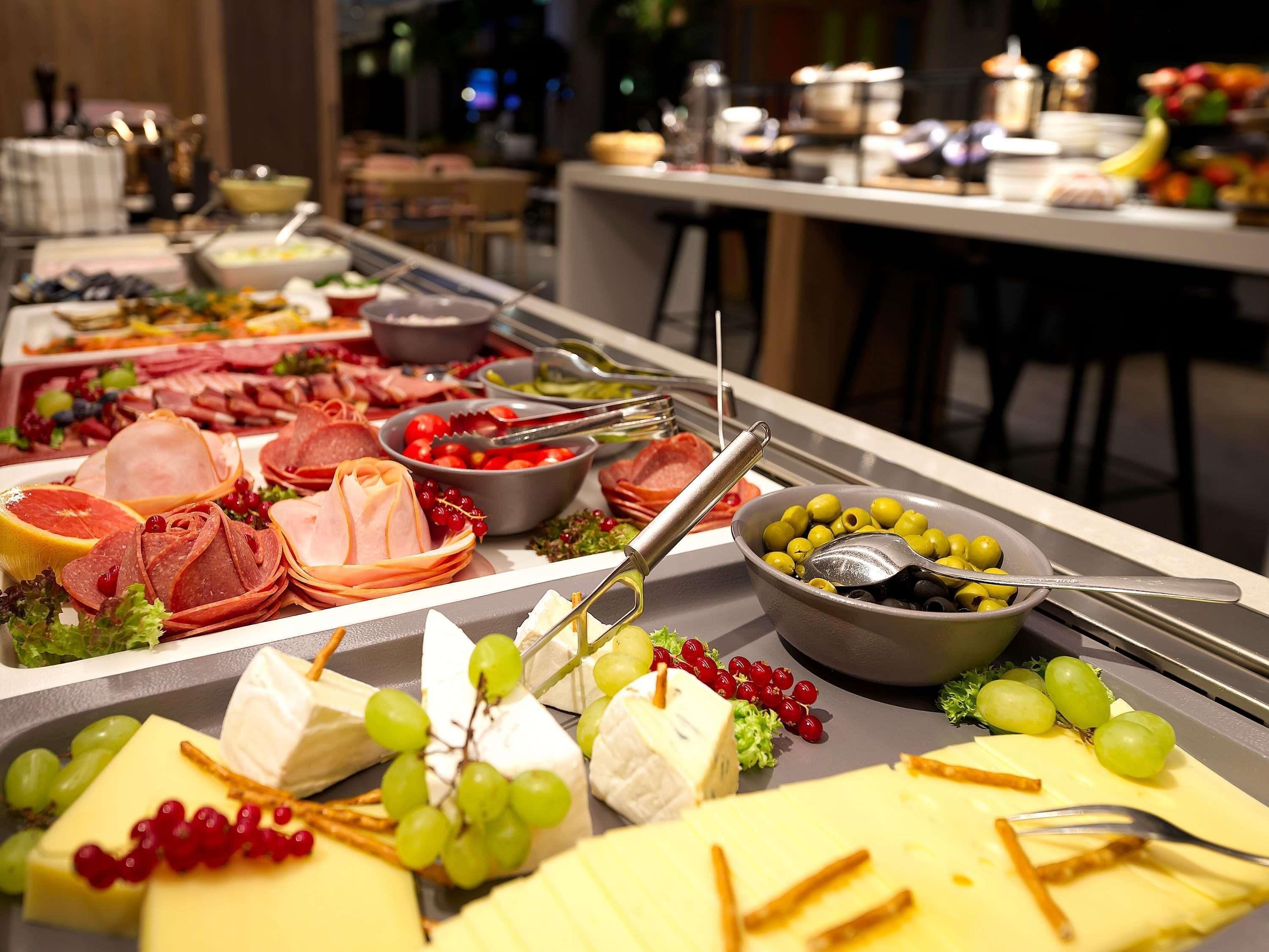 Un bufé con diversos quesos, carnes y frutas.