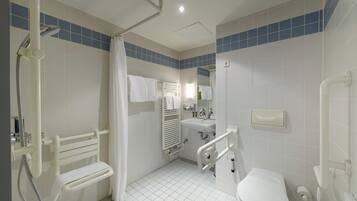 A bathroom with a shower, toilet, and sink, equipped with grab bars and a handrail.