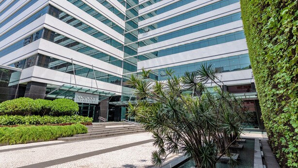 Un edificio moderno con fachada de vidrio y un jardín bien cuidado al frente.