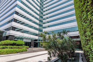 Un edificio moderno con fachada de vidrio y un jardín bien cuidado al frente.