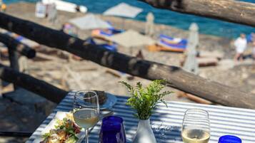 Enjoy a seaside meal with a view, featuring a delicious seafood plate, a glass of white wine, and a refreshing potted plant.
