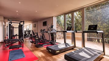 Un gimnasio con cintas de correr, bicicletas estáticas y máquinas de pesas.