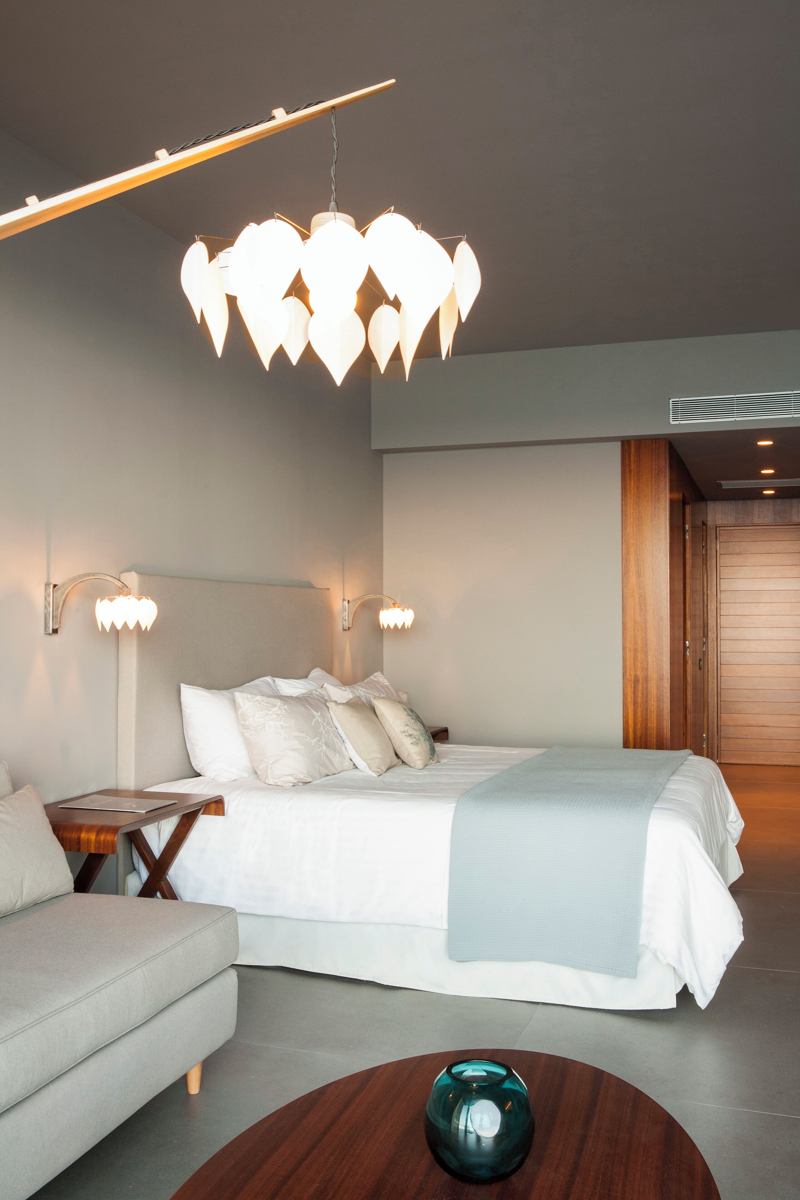Une chambre moderne avec un lit, des tables de chevet, un canapé et une table basse en bois.